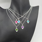 foto con 5 colgantes de plata de ley y esmalte de la colección bubble puestos sobre un maniquí. los colgantes son de color fucsia, verde, buganbilla, azul y agua