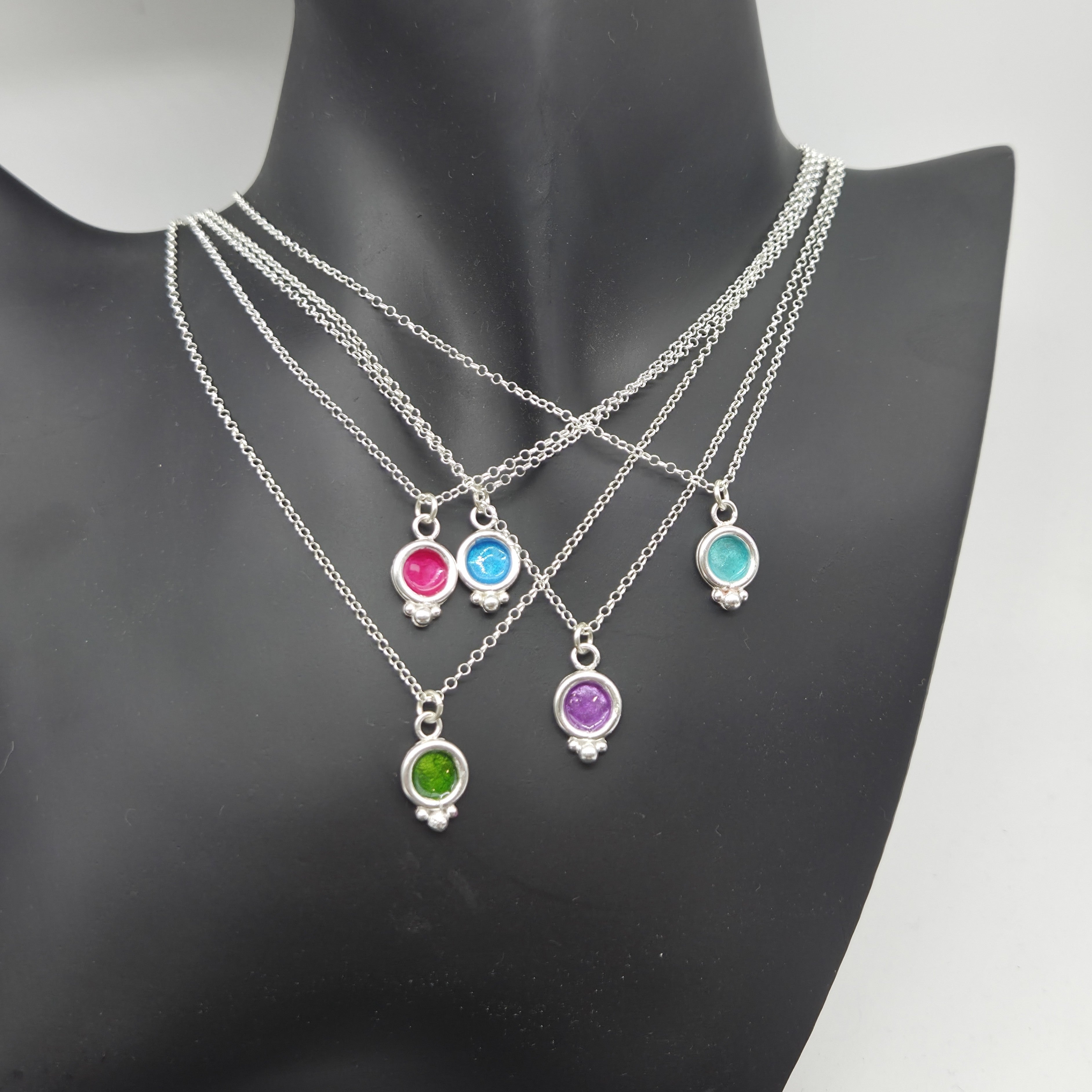foto con 5 colgantes de plata de ley y esmalte de la colección bubble puestos sobre un maniquí. los colgantes son de color fucsia, verde, buganbilla, azul y agua